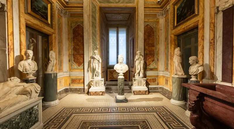 Roman emperor busts and classical sculpture in a Borghese Gallery room with mosaic floors