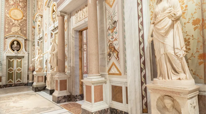 Frescoed corridor at the Borghese Gallery framing classical sculptures along inlaid marble floors